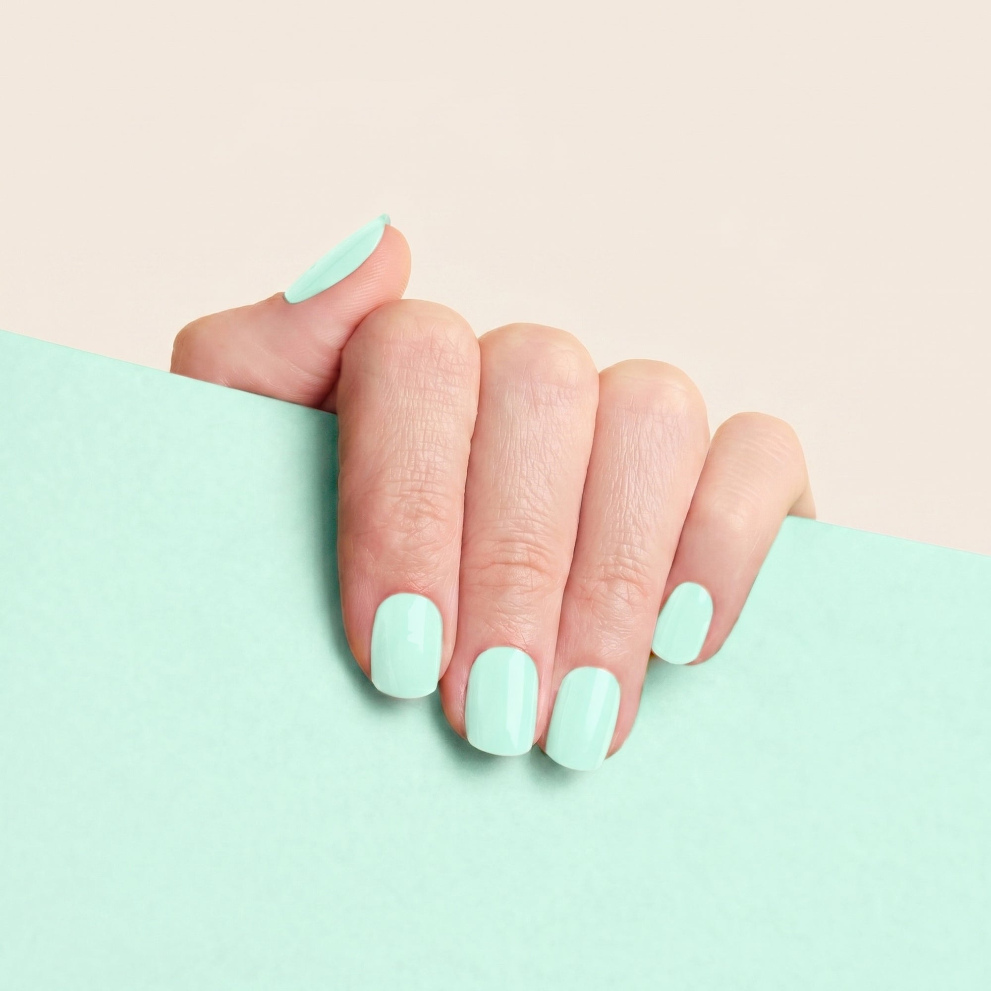 Hand with glossy seafoam mint mesme gel nail wraps against a matching mint background.