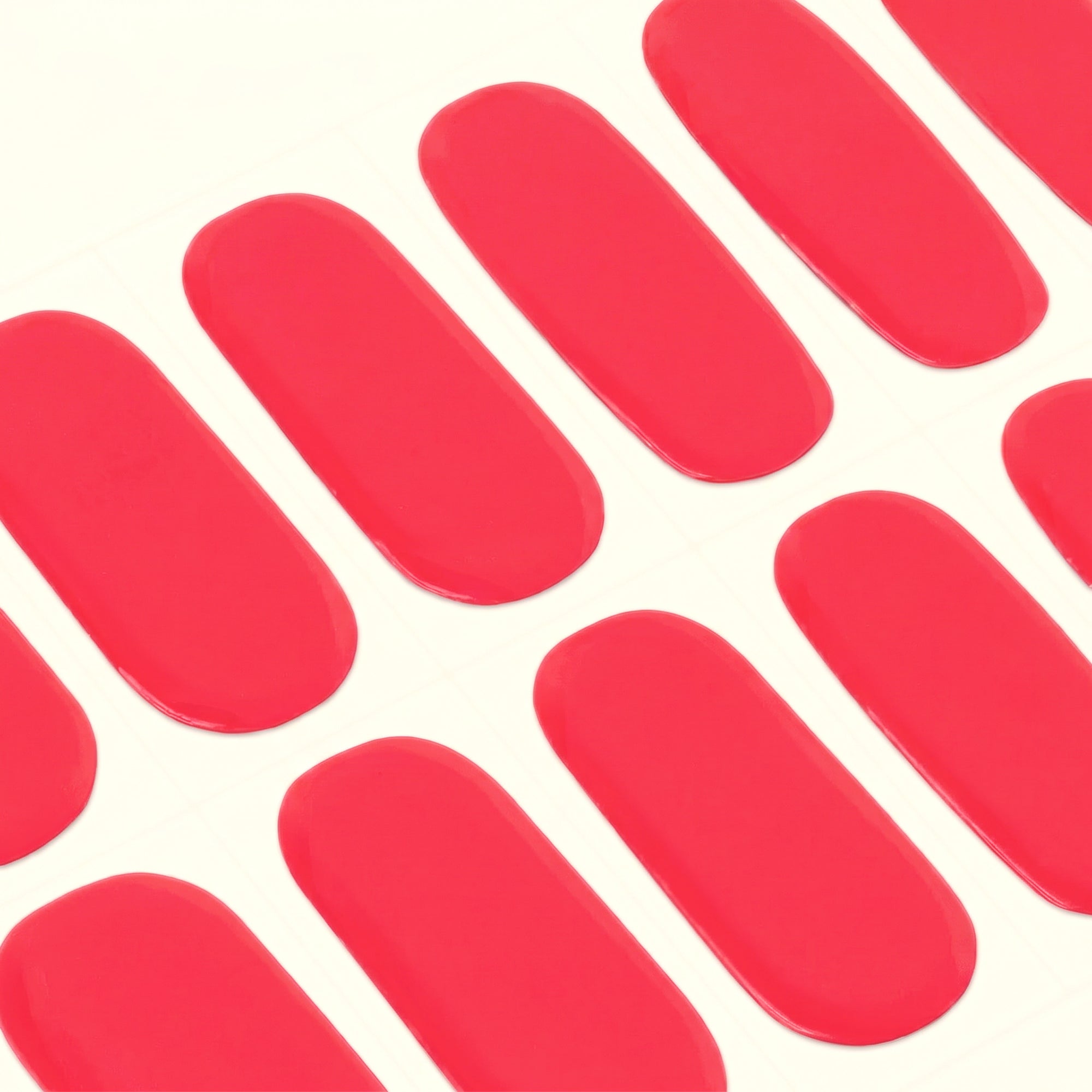 Close-up of glossy pink-red Danielle mesme gel nail wraps on a sheet.