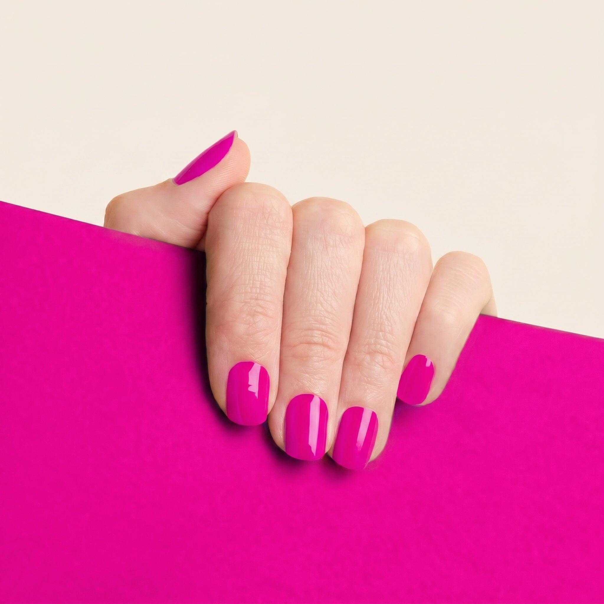 Hand with glossy bright pink mesme STAY nail wraps against a matching pink background.