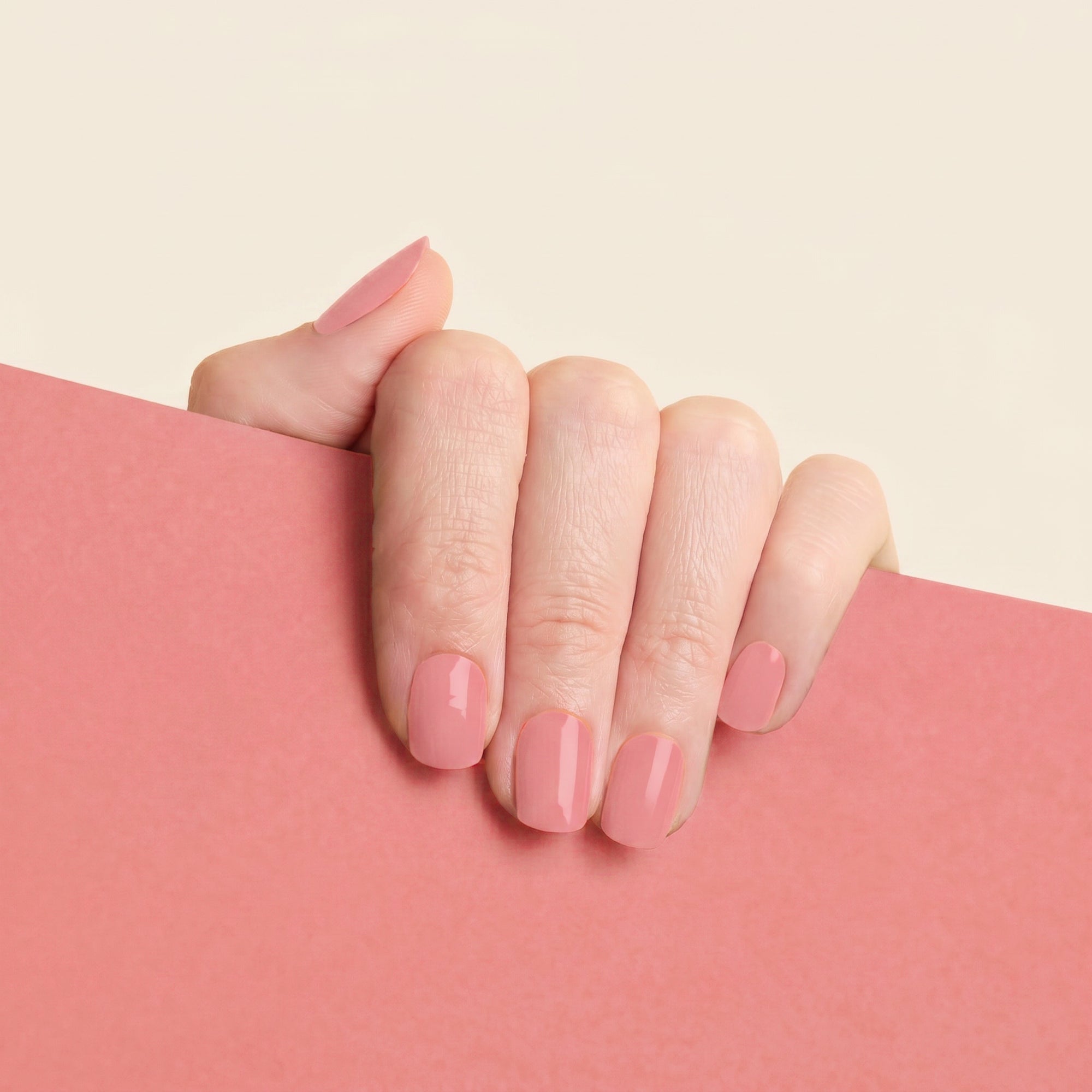 Hand with glossy blush pink mesme Martina STAY nail wraps against a soft pink background.