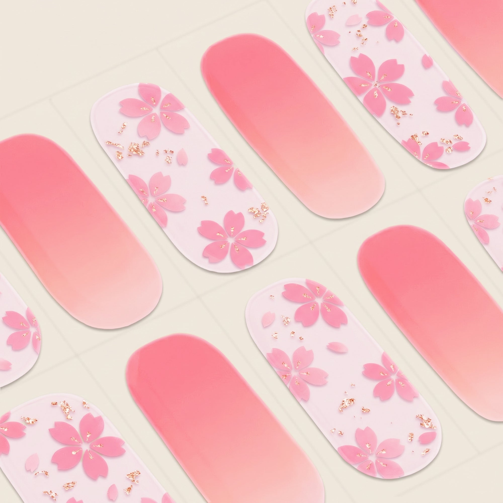 Close-up of Marianne mesme gel nail wraps with peach-pink ombré, pink floral details and tiny gold accents.