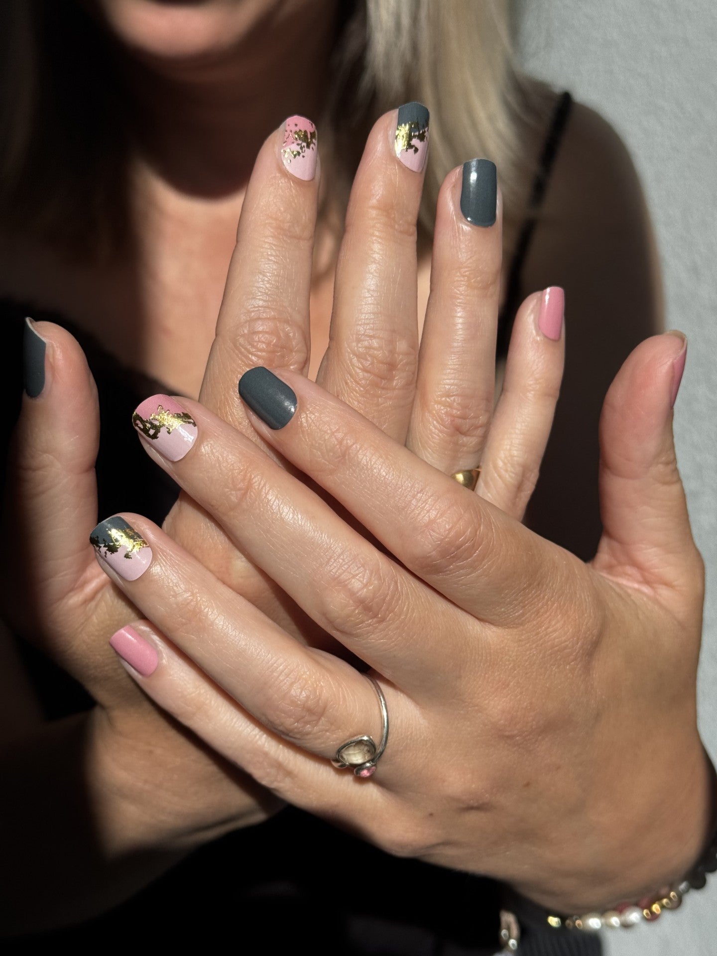 Close-up of a person's hands with mesme wrap nails, wearing rings.
